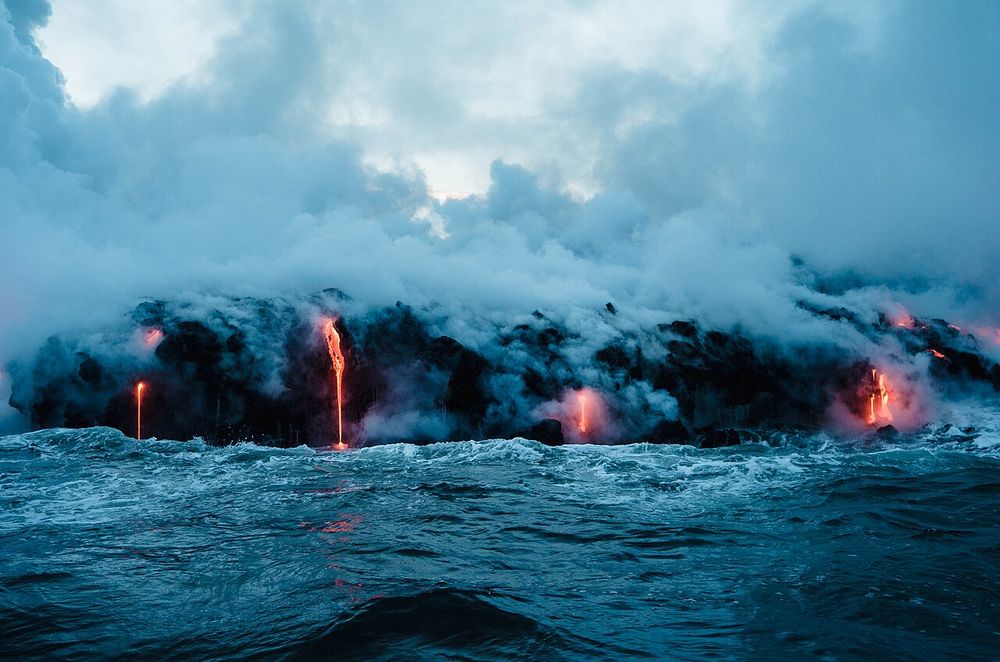 Lava pouring into the ocean beneath billowing steam on Hawaiʻi Island